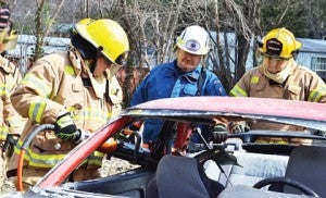 Star Photo/Rebekah Price  An Elizabethton firefighter slices the frame for the top of the car.